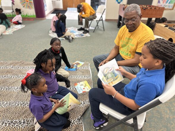 Volunteer reads with four young girls.